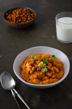 Kalın balkabağı çorbası, pişmiş nohut ve bir tabakta turp lahanası, masada bir bardak süt, lezzetli sağlıklı bir akşam yemeği.