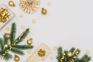 Altın madalyalı şenlikli arka plan, yeşil ladin dalları ve hediye kutuları, kağıt noel ağacı süslemeleri, ışıltılı kar taneleri ve noel baloları.