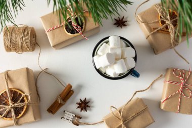 Şenlikli noel masası üst görünümü, çam dalları ve marşmelovlu kupa, hediye kutuları ve kurutulmuş narenciye, yıldız anasonlu tarçın