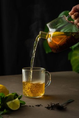 Sıcak siyah çayı naneli, limonlu ve limonlu kadın çaydanlıktan cam bardağa, akşam çay partisine katıyor.