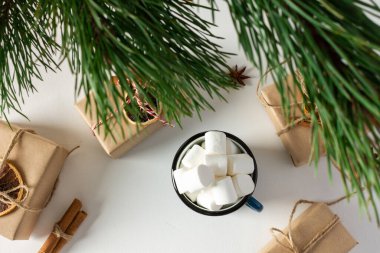 Şenlikli noel masası üst görünümü, çam dalları ve marşmelovlu kupa, hediye kutuları ve kurutulmuş narenciye, yıldız anasonlu tarçın