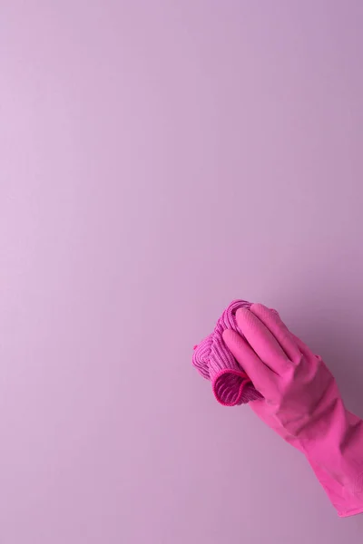 手拿着粉红橡胶手套的人拿着一块微纤维布在紫色的背景上洗 — 图库照片