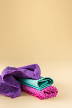 Tarafsız bir bej arka planda yıkanmak için çok renkli mikrofiber kumaşlar, temizlik konsepti.