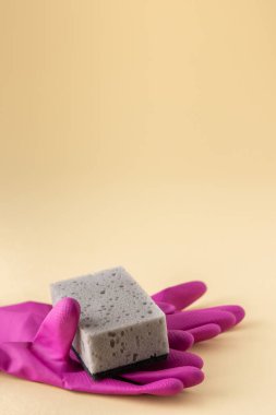 Tarafsız bej arka planda gri bulaşık süngeri ve pembe lastik eldivenler, temizlik konsepti