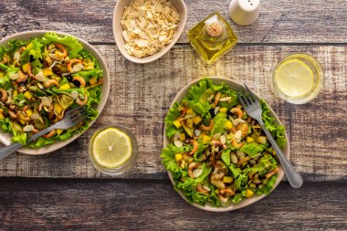 Lezzetli hafif akşam yemeği, kızarmış kabak dilimli marul, mango, karides ve badem yaprağı, bardakta limonlu su.