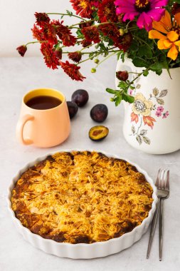 Badem taneli ev yapımı erik keki, vazoda sonbahar çiçekleri.