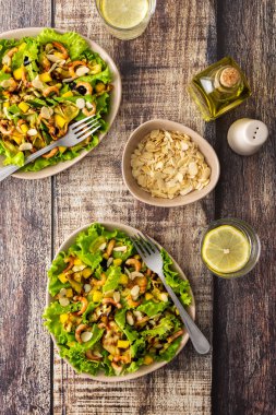 Lezzetli hafif akşam yemeği, kızarmış kabak dilimli marul, mango, karides ve badem yaprağı, bardakta limonlu su.