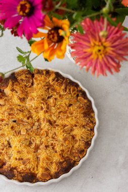 Badem taneli ev yapımı erik keki, vazoda sonbahar çiçekleri.