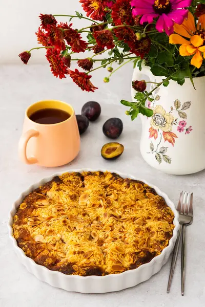 Badem taneli ev yapımı erik keki, vazoda sonbahar çiçekleri.