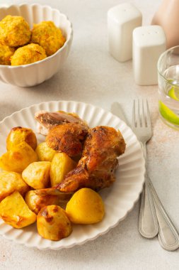 A delicious meal featuring roasted rabbit paired with golden-brown potatoes creates a hearty main course. Accompanying the dish are vibrant chickpea buns and a fresh salad