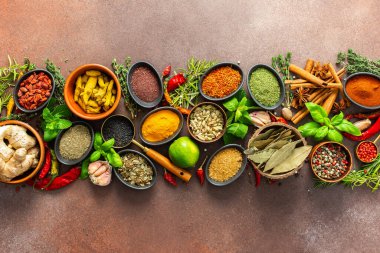 Taze baharat ve otlardan oluşan nefes kesici bir serpinti, titizlikle kahverengi bir zemin üzerine yerleştirilmiş, canlı renklerini ve aromalarını yakalıyor.