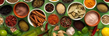 Renkli baharatlar ve bitkiler narin yeşil bir arka planda sergilenmiş, canlı doğal bir görünüş için tazeliklerini ve kokularını vurguluyorlar.