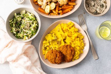 Enjoy a flavorful meal featuring rice topped with rhubarb fried eggs, baked sweet potato, and colorful veggies. Fresh salad and crispy meat fritters complete this delightful dish