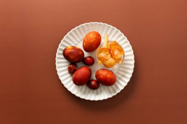 Renkli yumurtalar, küçük bir kase soğan kabuğuyla birlikte bir tabağa konur. Yumurtaların kahverengiye boyanması evde Paskalya toplantısı için şenlikli bir atmosfer yaratır..