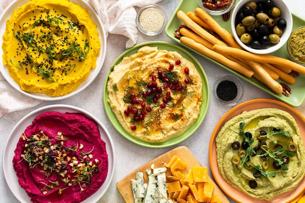 Canlı bir yayışta klasik, pancar, brokoli ve zerdeçal gibi farklı türde humus sergilenir. Yanında zeytin ve ekmek çubukları ile birlikte, paylaşımı ve eğlenceyi davet eder