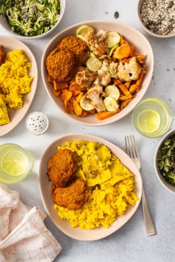 Pirinç, kızarmış yumurta, fırında tatlı patates ve sotelenmiş karnabahar ve kabak içeren renkli bir ziyafet..