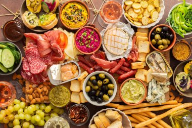 Çeşitli peynirler, lezzetli sosisler, kremalı humus, fındık ve renkli sebzelerle dolu canlı bir şarküteri tahtasının tadını çıkarın. Sıradan bir toplantıda paylaşmak için mükemmel.