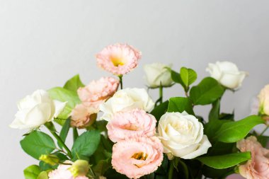 Bir buket taze çiçek pembe bir yüzeyde beyaz bir sürahi içinde düzenlenir. Çiçekler pembe ve beyaz çiçeklerle birlikte yeşil yaprakları da içerir.