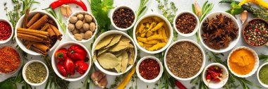 Gri bir arka planda sıralanmış çeşitli baharat ve otlar, her yemeğe derinlik ve aroma katan doğal tonlara sahip, afiş