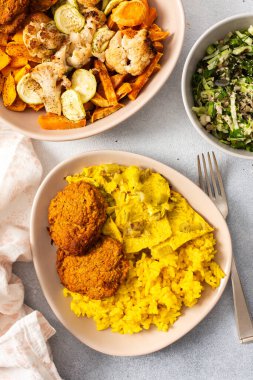 Pirinç, kızarmış yumurta, fırında tatlı patates ve sotelenmiş karnabahar ve kabak içeren renkli bir ziyafet..