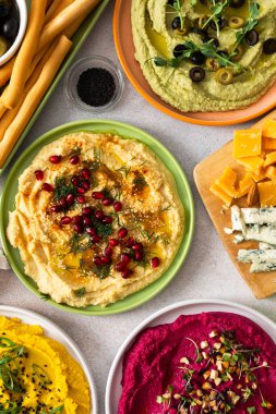 Canlı bir yayışta klasik, pancar, brokoli ve zerdeçal gibi farklı türde humus sergilenir. Yanında zeytin ve ekmek çubukları ile birlikte, paylaşımı ve eğlenceyi davet eder