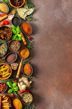 Baharat ve otların uyumlu bir karışımı, renkler ve kokularla dolu, kahverengi bir arka plana yayılmış, aşçılık sanatını çağrıştırıyor.