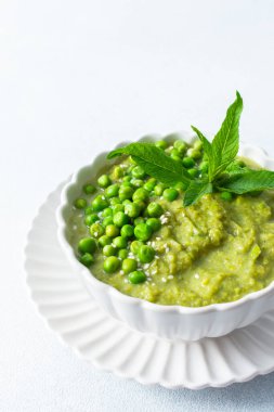 Bir kase canlı yeşil bezelye ve brokoli çorbası lezzet için taze nane yapraklarıyla kaplıdır. Bu sağlıklı yemek sıcak bir öğle yemeği ya da evde sıcak bir akşam yemeği için mükemmel.