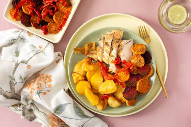 Fırında patates, tavuk göğsü, kızarmış havuç, biber ve pancar ile servis edilir. Basit bir masada hafif bir yemek düzenlenir..