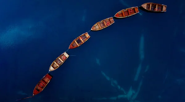 An aerial perspective beautifully showcasing an array of colorful boats gracefully aligned on calm blue waters