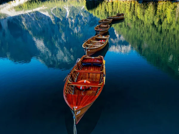 Güzel ahşap tekneler sakin bir göle dizilmişler. Etraflarında çarpıcı dağ yansımaları sergiliyorlar.