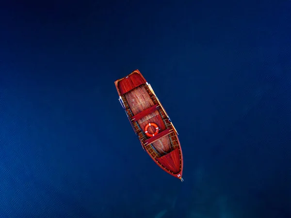 Bir hava görüntüsü, sakin mavi sularda yüzen kırmızı bir tekneyi yakalıyor. Huzur ve yalnızlığı çağrıştırıyor..