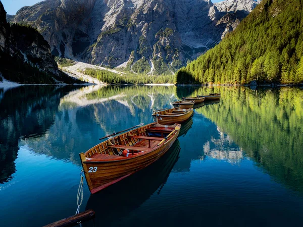 Berrak bir dağ gölünde, gür ormanlarla çevrili ahşap teknelerin olduğu sakin bir manzara..