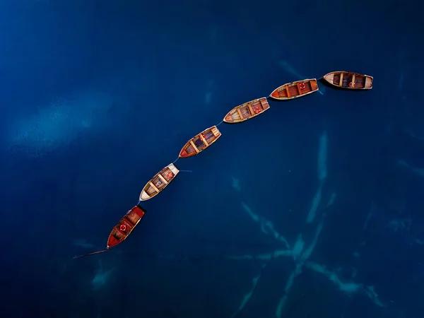 Beautifully arranged boats are floating gracefully on calm, serene blue waters, creating a picturesque scene