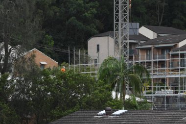 56-58 Beane St. Gosford, Avustralya 'daki yeni sosyal konut bloğunda yapı iskelesi yapan bir inşaat işçisi. 27 Şubat 2021. İnşaat serisinin bir parçası.