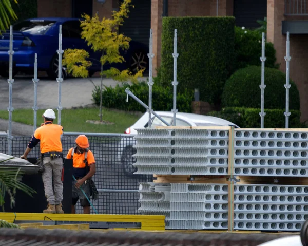 İnşaat işçileri PVC ile kapatıyorlar. Yeni sosyal konut alanı 56-58 Beane St. Gosford, Avustralya 'daki Duvar Formwork malzemeleri. 18 Şubat 2021. Bir serinin parçası