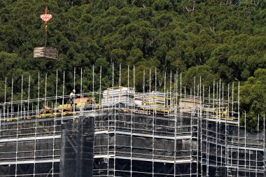 Avustralya 'daki 56-58 Beane St. Gosford' daki yeni bloğun en üst katında işçiler, kat döşemeleri ve PVC beton duvar formlarını birleştiriyor. 10 Nisan 2021. Bir serinin parçası.