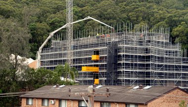 Beton Patlama Pompası, çalılık zemini olan yeni şantiyeye malzeme getiriyor. 56-58 Beane St. Gosford 'da yeni sosyal konutlar. Avustralya. 17 Nisan 2021. Dizinin bir parçası. Ticari imaj. 