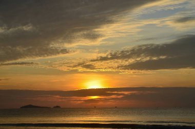 Göz kamaştırıcı, parlak renkli, altın stratocumulus bulutlu, tropikal okyanus güneş doğumu deniz manzarası ve okyanus suyu yansımaları. Huay Yang, Tayland.