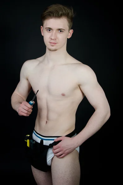 Young sexy handyman. Naked boy. Posing in studio. Black background. — Stock Photo, Image