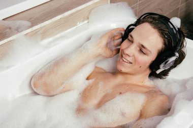 Genç çekici adam köpüklü bir küvette dinleniyor..