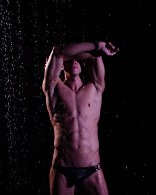 Duşun altında sırılsıklam genç yakışıklı bir adam..