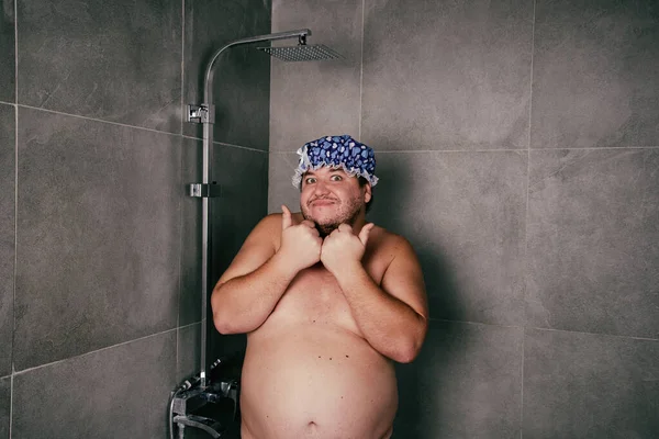 Funny fat man washes in the shower.