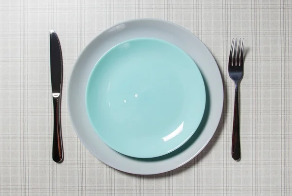 Empty plate with table items. Empty plate.On the table is a white empty plate, a knife and fork on a linen napkin with a beautiful pattern. Top view, copy locatio — Stock Photo, Image