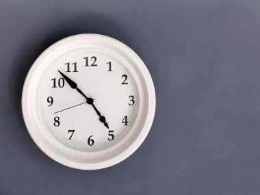 A white round clock on a gray background. Space for the text. Copy space
