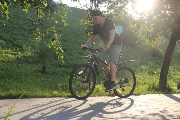 Chlápek jezdí na kole v parku. Mladý fit muž během jízdy na kole za slunečného dne. Rozmazané zaměření — Stock fotografie