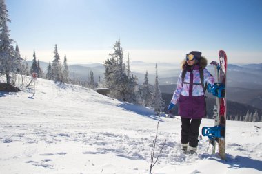 Kayak ekipmanlı bir kadın bir dağın tepesinde duruyor. Kayak merkezinde bir kız.
