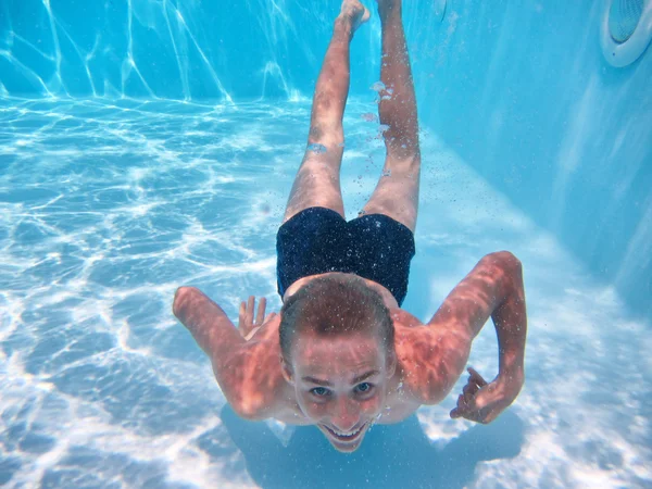 Happy teenage boy dives in a pool — Stock Photo, Image