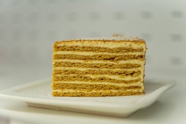 Beyaz tabakta bir parça bisküvi. Ballı kek.