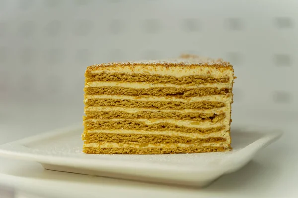 Een Stuk Biscuitcake Een Wit Bord Honingtaart — Stockfoto