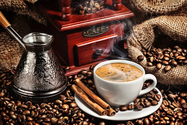 Tasse Kaffee, Mühle, türkische und Kaffeebohnen auf braunem Hintergrund lizenzfreie Stockfotos